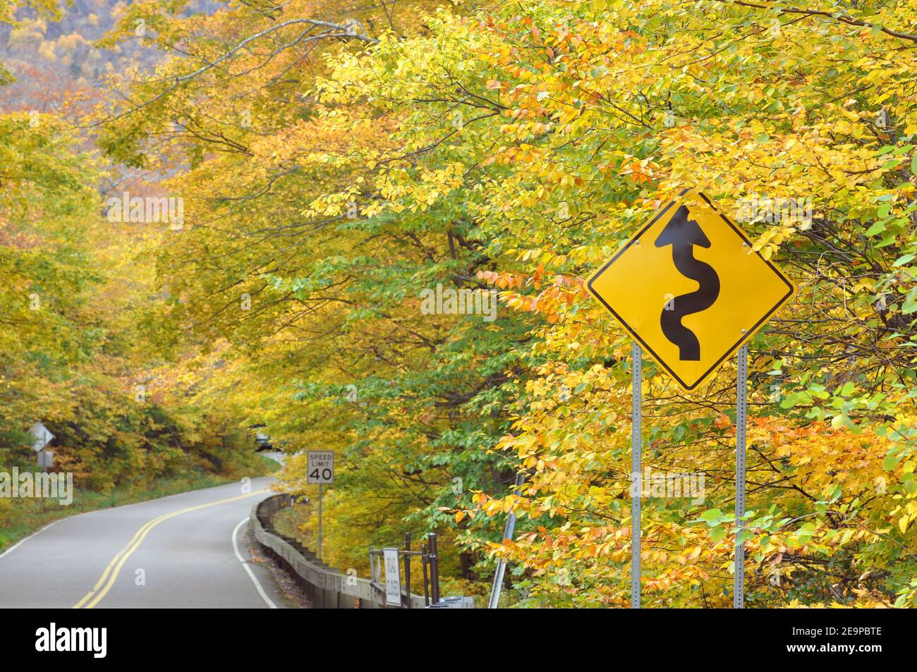Curve road sign on Vermont Route 108 with Fall Foliage at Smugglers Notch in town of Cambridge, Vermont VT, USA. Stock Photo