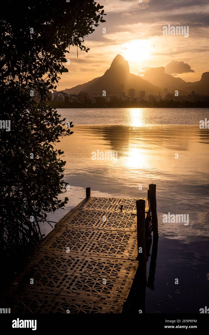 Beautiful view to small pier during sunset by lagoon with mountains and bushes, in Rio de Janeiro, Brazil Stock Photo