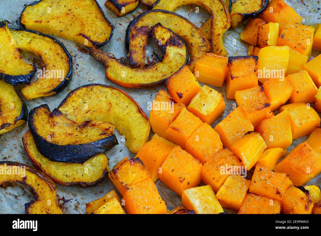Roasted butternut squash cubes and acorn squash slices on parchment
