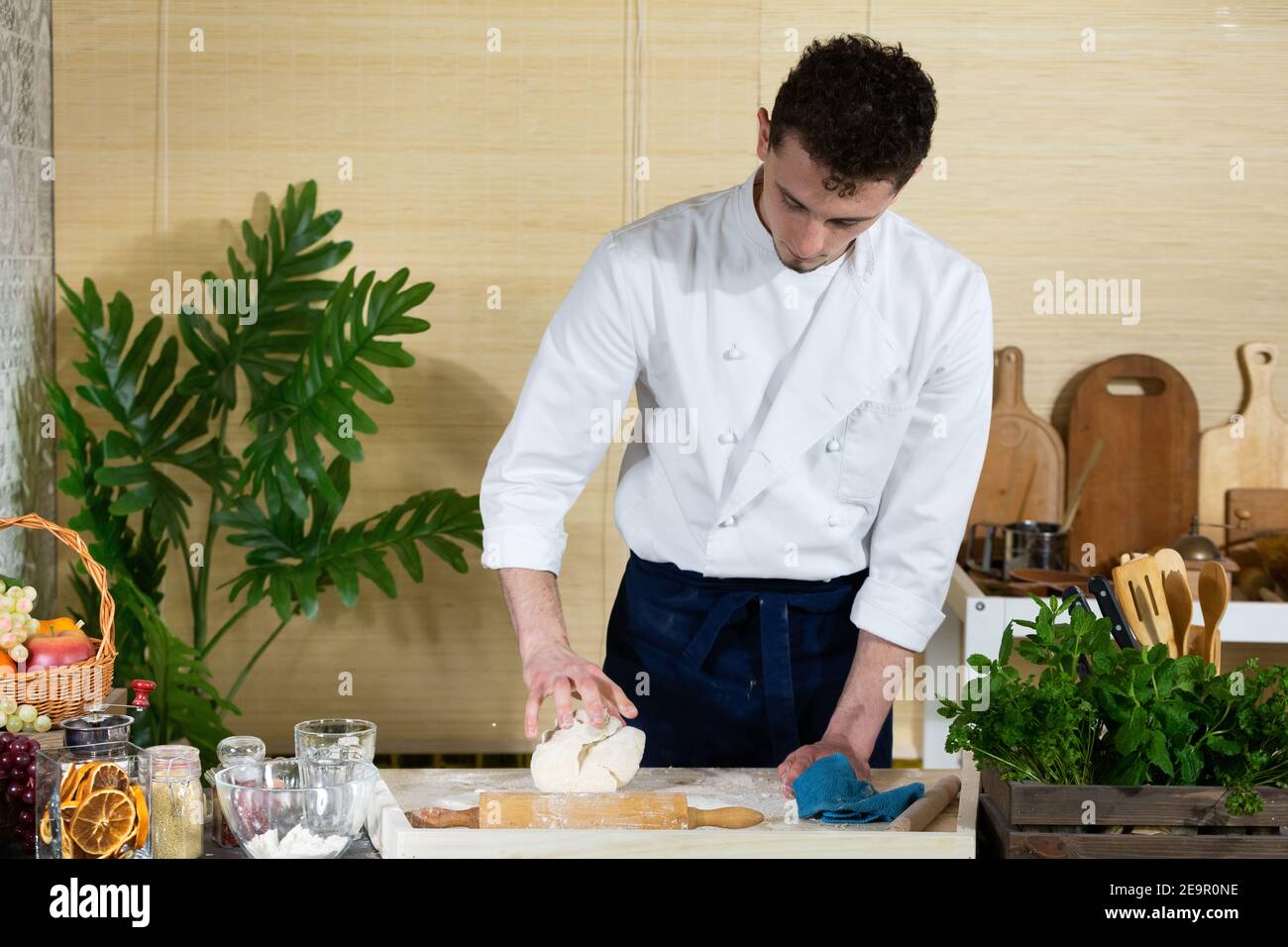 A handsome cook stands behind the board by the kitchen counter