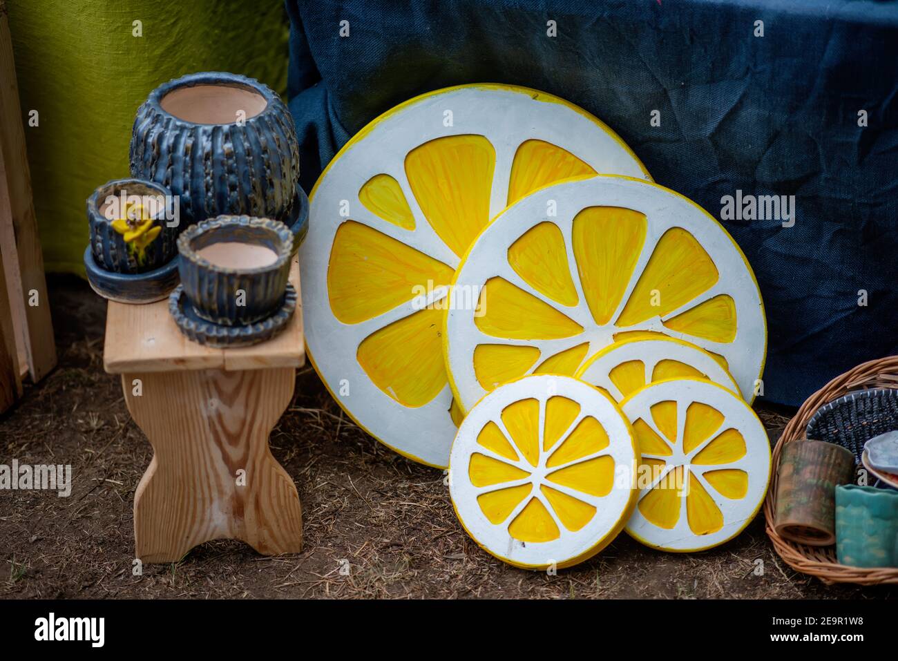 At the festival street fair, handmade wood products are sold: flowerpots, stools, decorative elements in the form of yellow lemons, candlesticks. Stock Photo