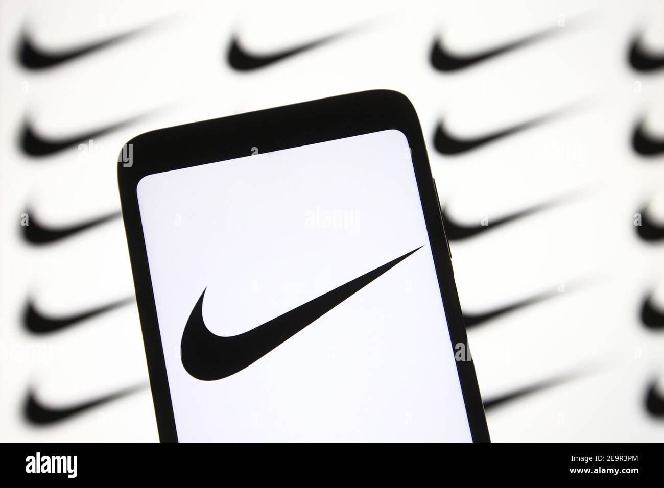 In this photo illustration a Nike logo is seen on a mobile phone and a pc  screen Stock Photo - Alamy