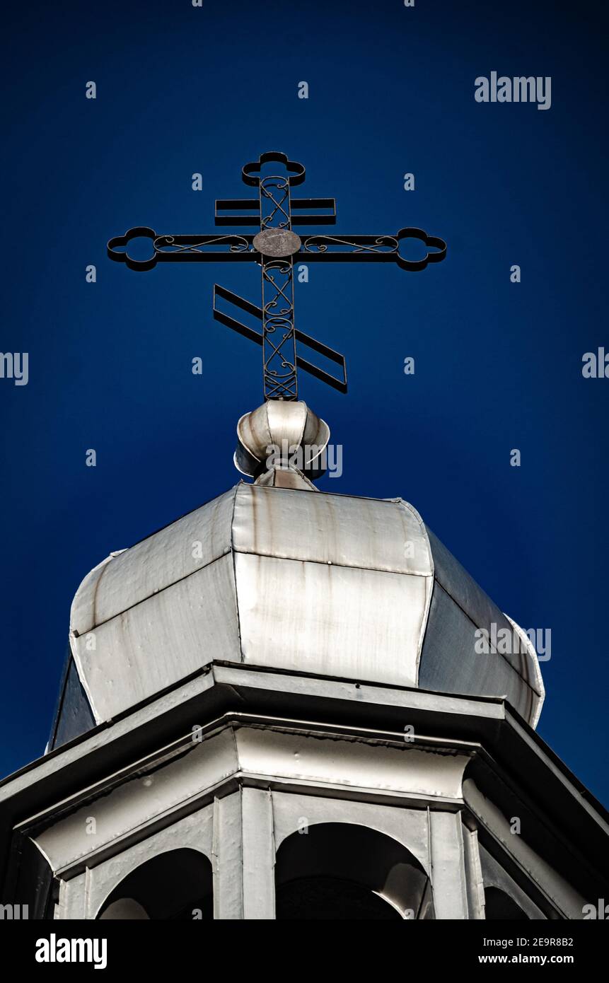 Low angle shot of a cross on the church's metallic dome under the blue ...