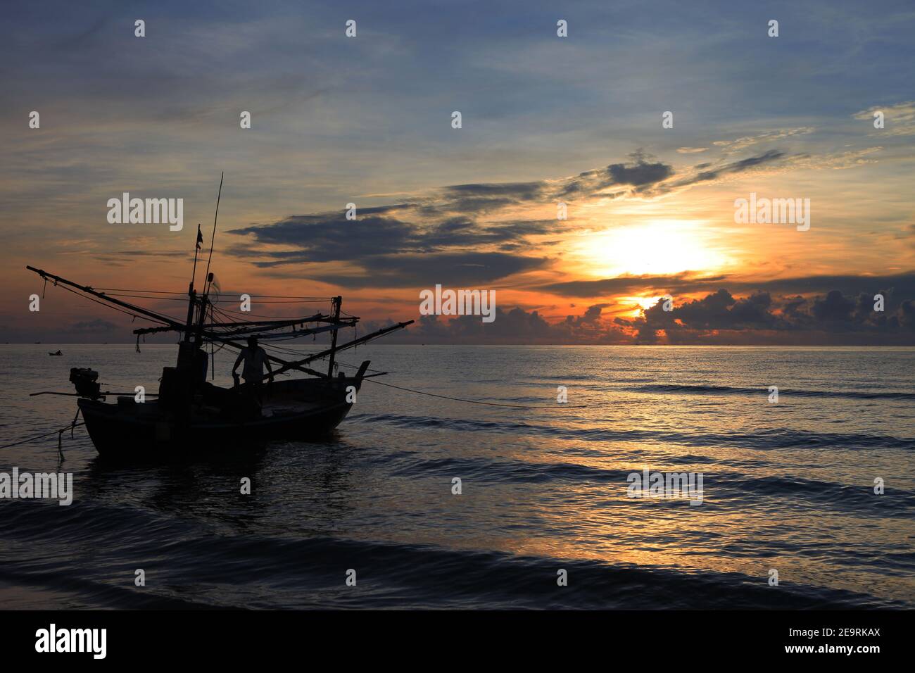 The silhouette of a fishing boat floats on the water in the morning ...