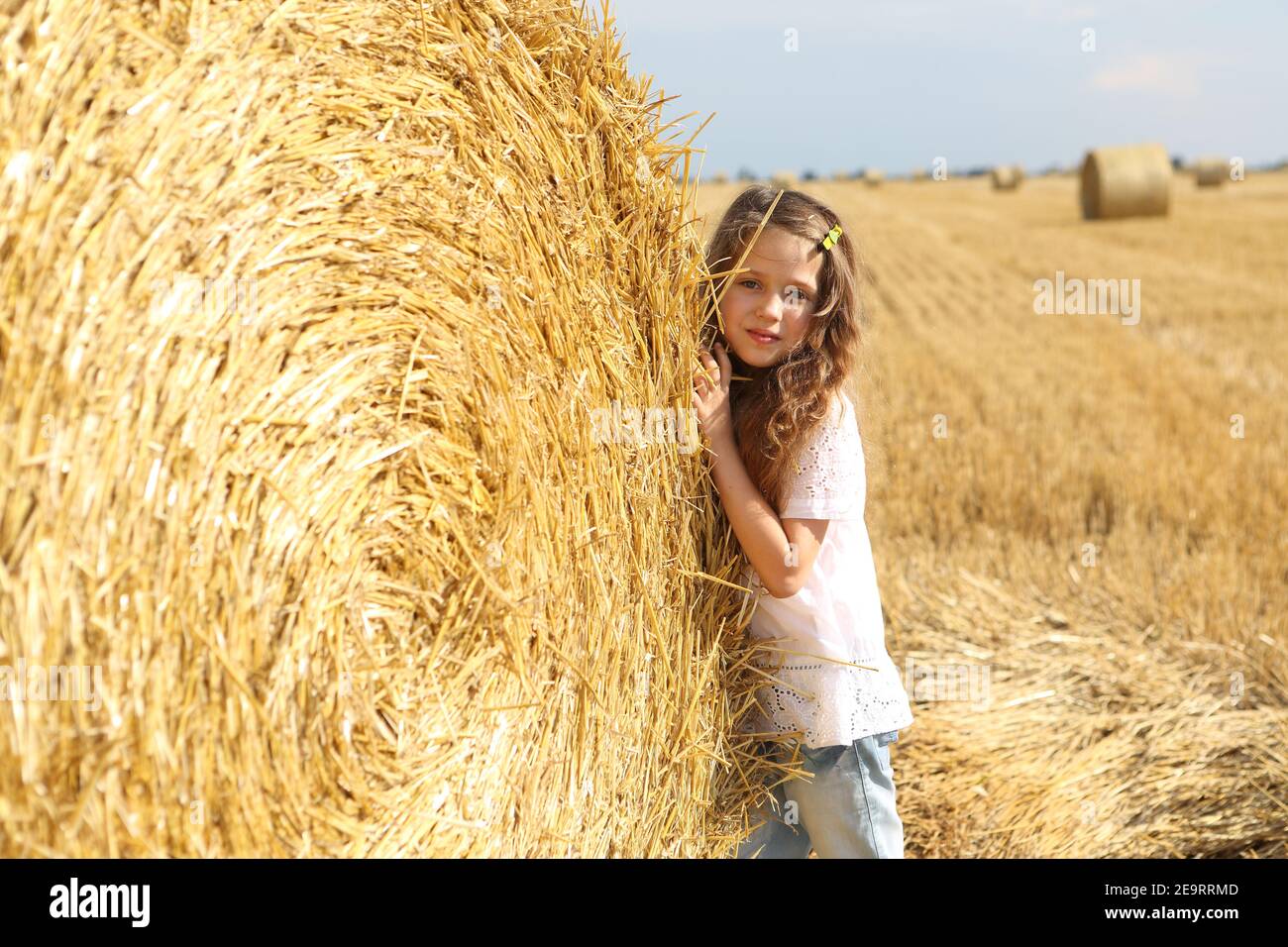 Little girl near a haystack in a field Stock Photo - Alamy