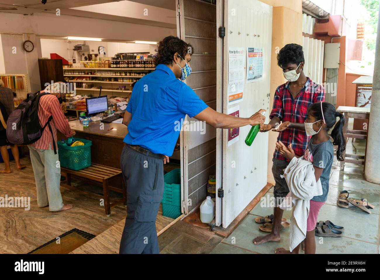 AUROVILLE, INDIA - 3 April 2020: Cleaning hands before entering a minimarket to get some food during the lockdown caused by the coronavirus. Stock Photo