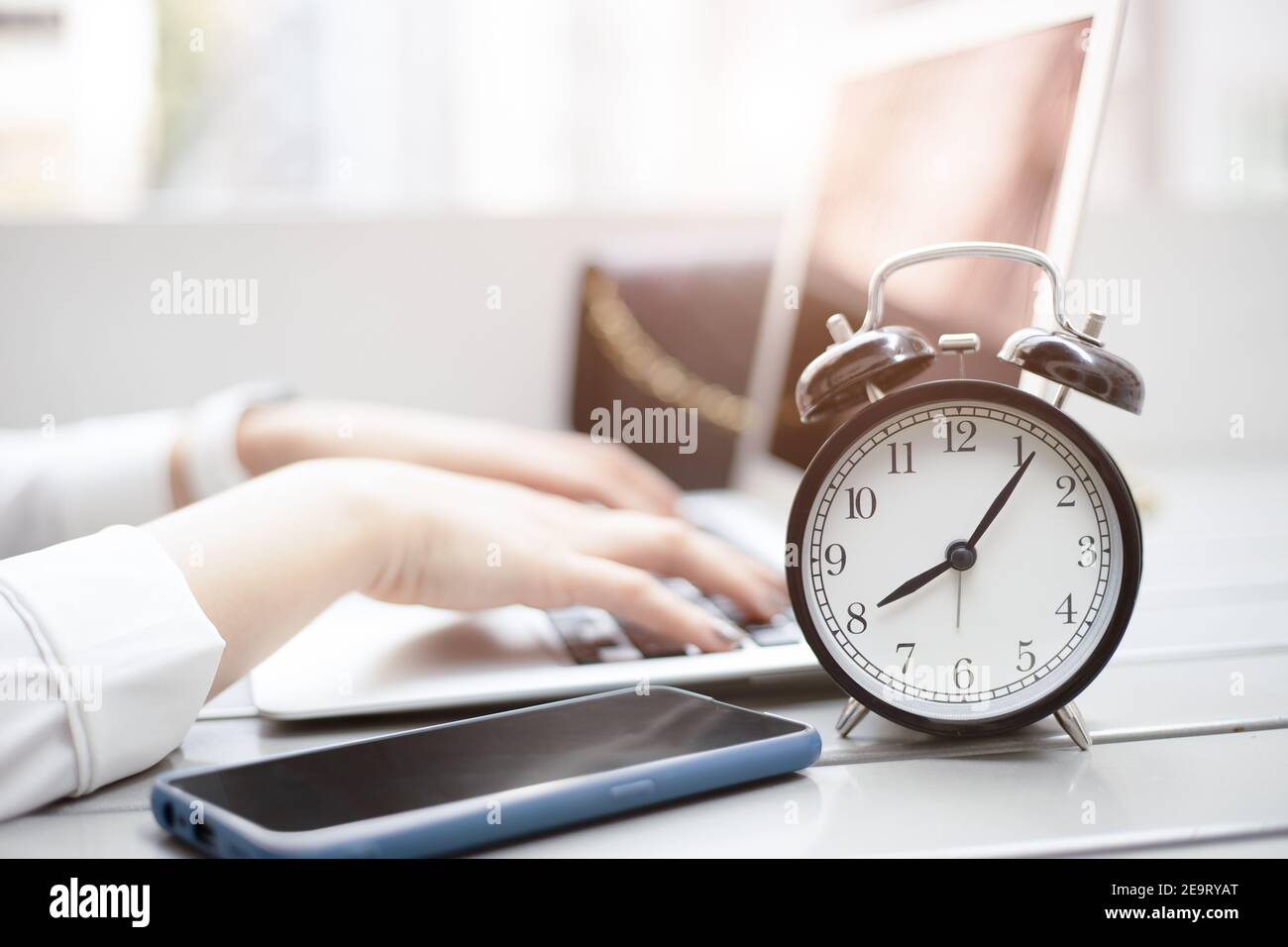 Business working times concept people work typing on laptop computer overlay with in time clock in the morning Stock Photo
