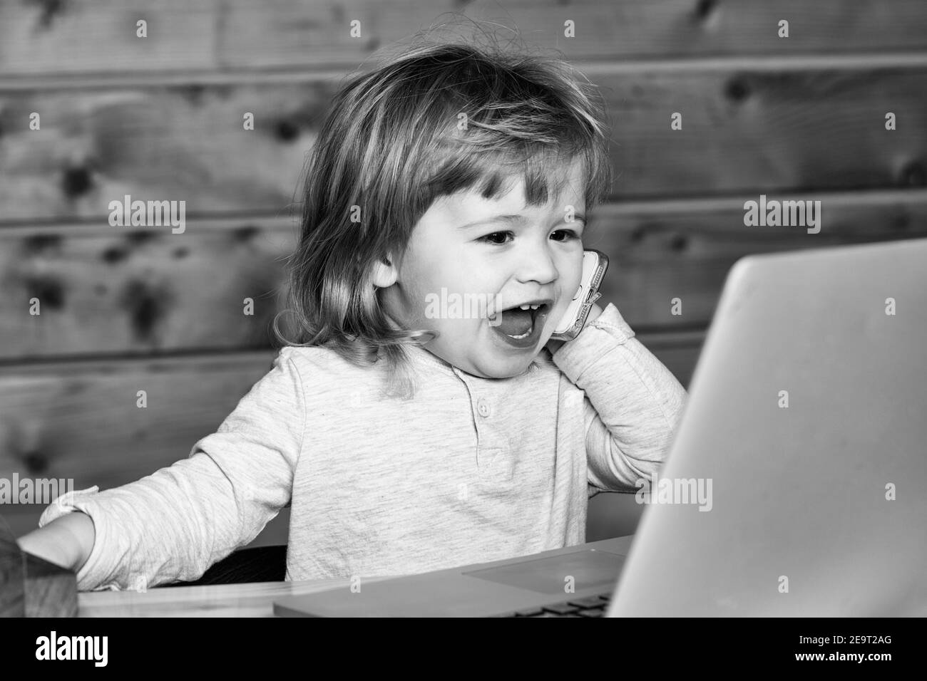 Cute emotional funny little baby boy speaking by mobile phone near