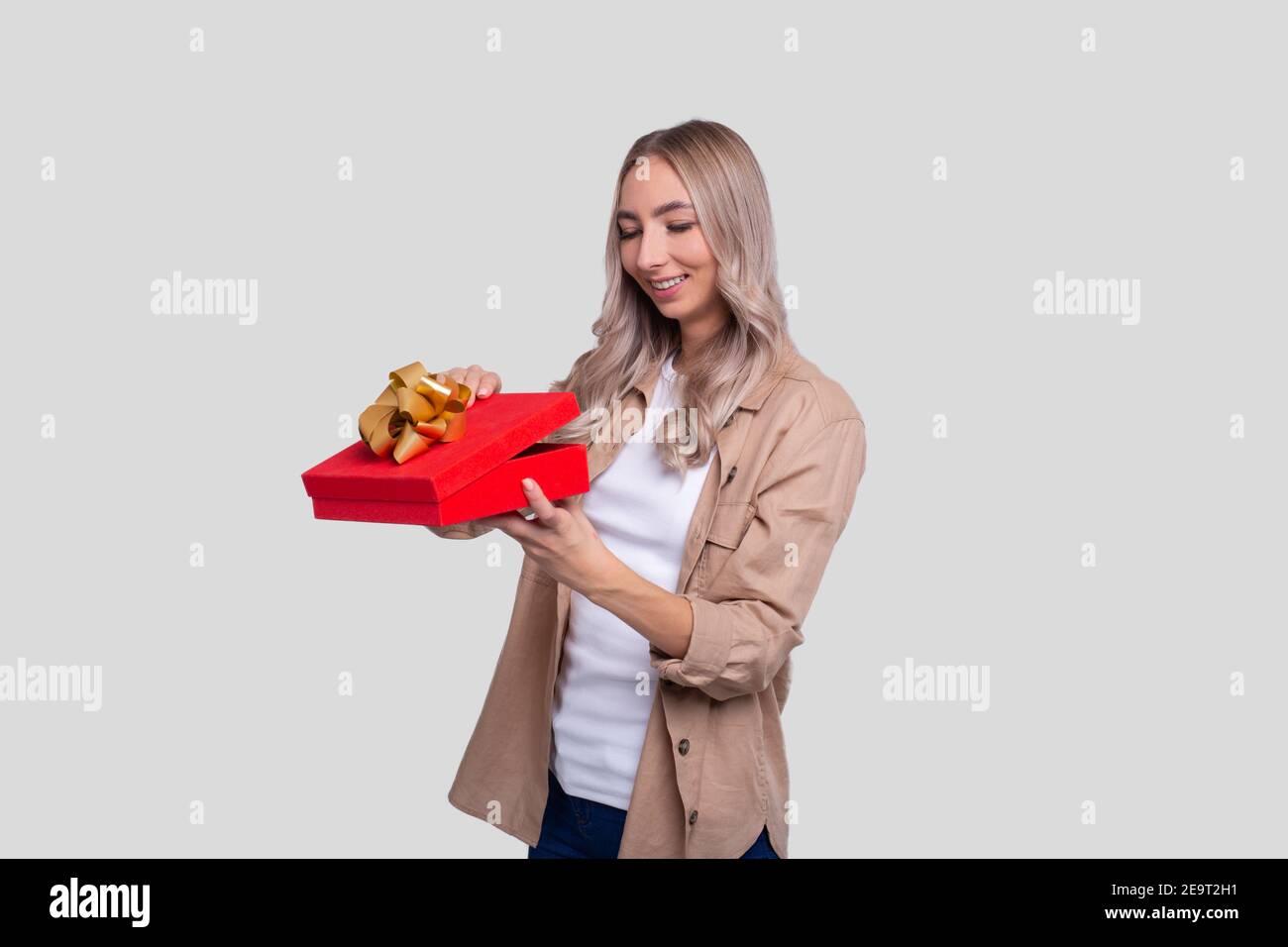 Girl Holding Present Watching Whats inside. Girl Holding Gift. Stock Photo