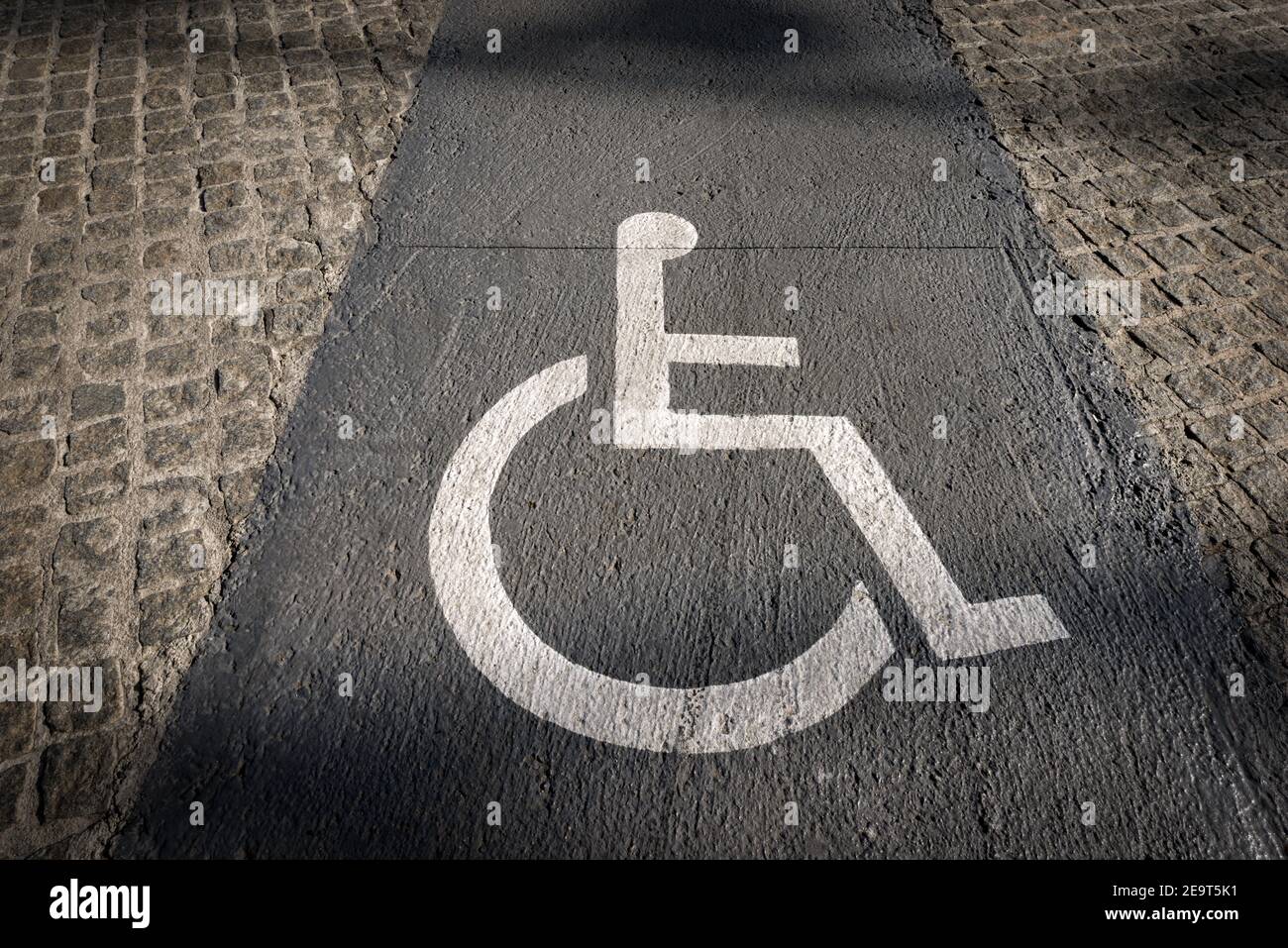 Lane reserved for wheelchairs in the city of Barcelona with a white (Accessibility for Persons with Disabilities) symbol painted on the gray concrete. Stock Photo