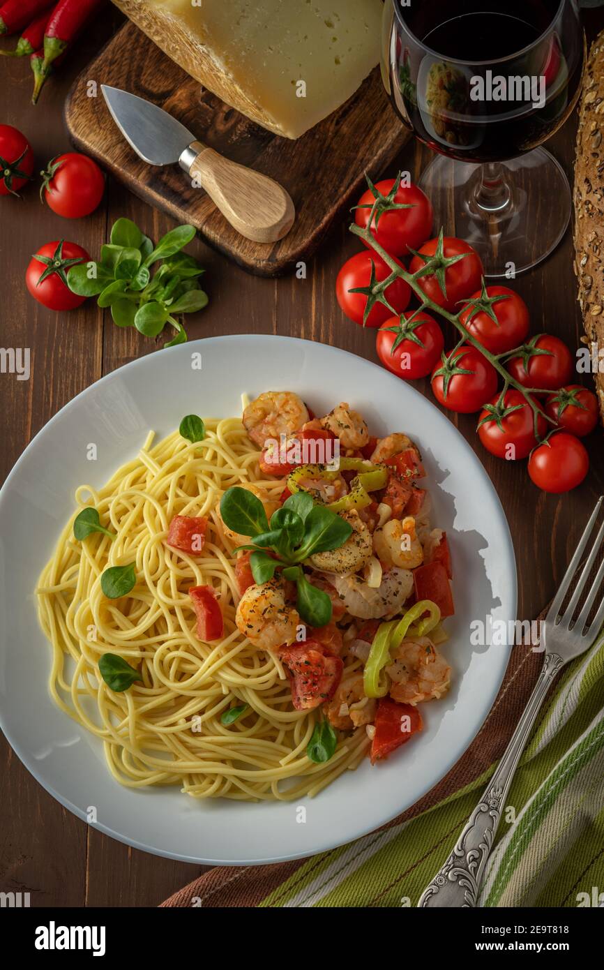 Spaghetti with shrimps, cherry tomatoes and spices on wooden background. Food background. Top view. Stock Photo
