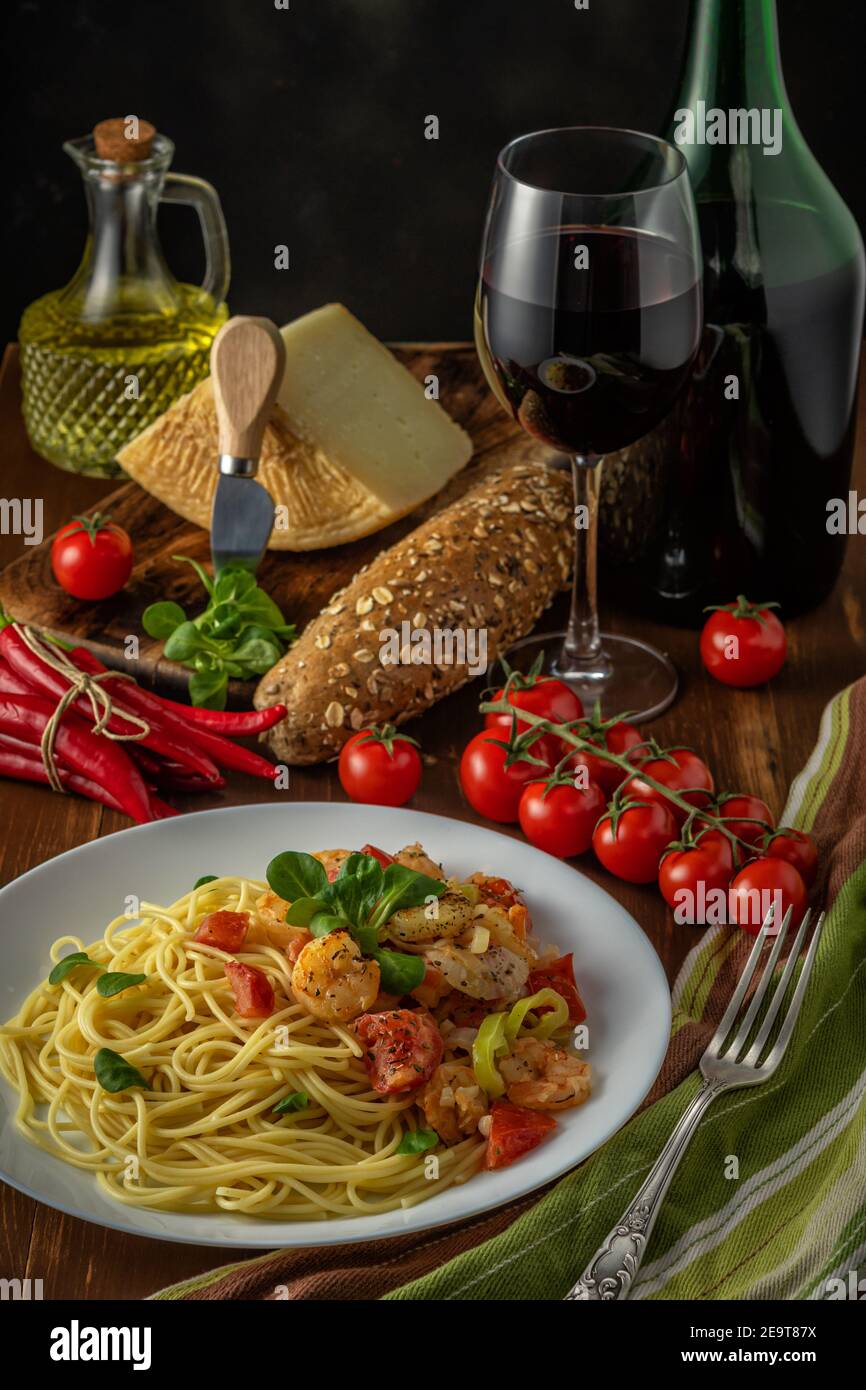 Spaghetti with shrimps, cherry tomatoes and spices on wooden background. Food background. Stock Photo