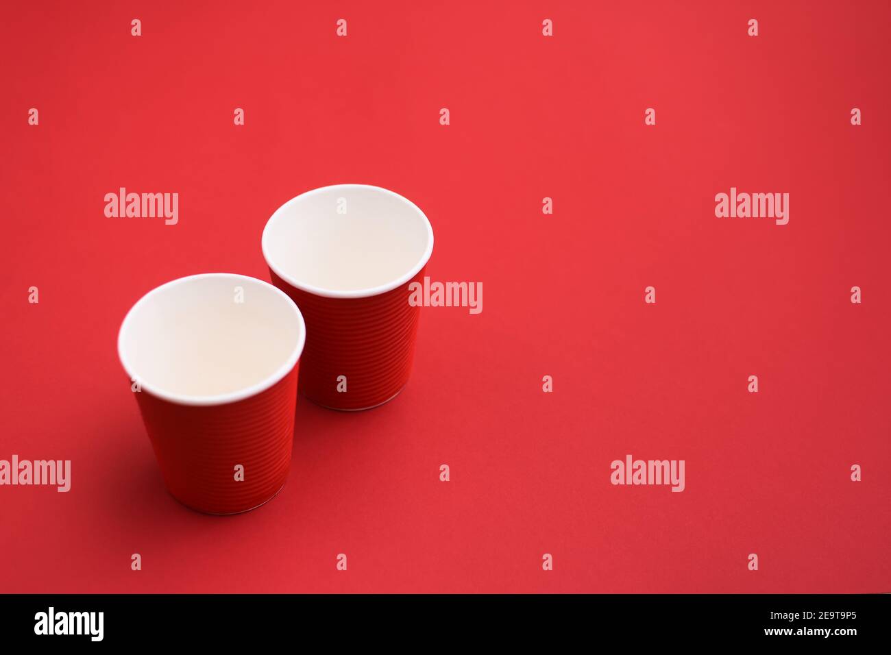 two red cardboard empty coffee glasses. two paper cups on red background. Stock Photo