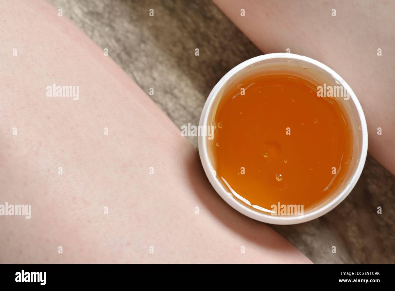 Sugar paste in a jar between the legs of a woman. Depilation Sugaring. Beauty and skin care concept. Stock Photo