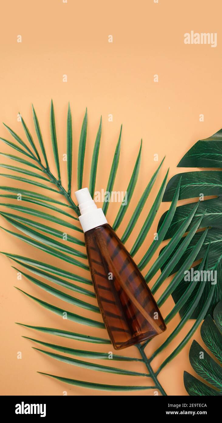 Suntan lotion bottle on soft orange background with tropical leaf. Top ...