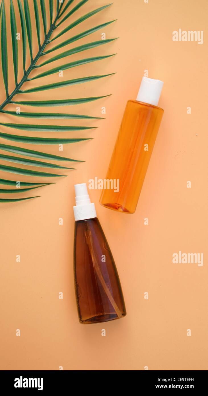 Suntan lotion bottle on soft orange background with tropical leaf. Top ...