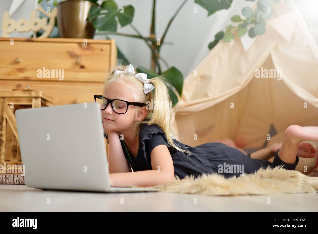 Little girl with laptop on the floor in her room Stock Photo