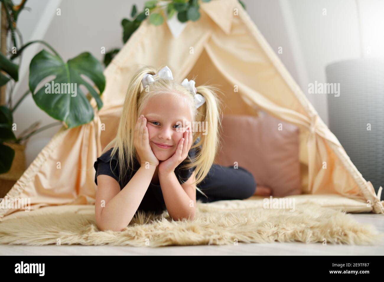 Little girl with a smile in her room on the floor next to the wigwam tent Stock Photo