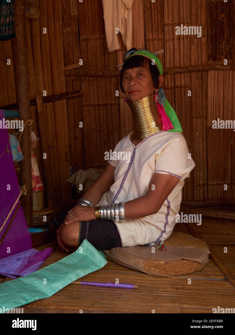 Portrait of a Karen hill tribal woman with distinctive accessories on her long neck sits posing on the porch of her house Stock Photo