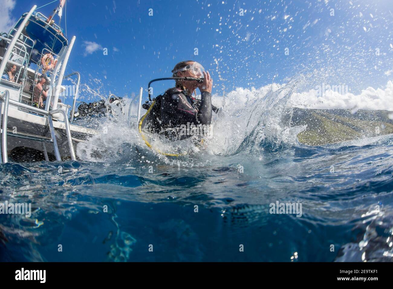 A diver (MR) steps off a dive boat into the Pacific Ocean out from