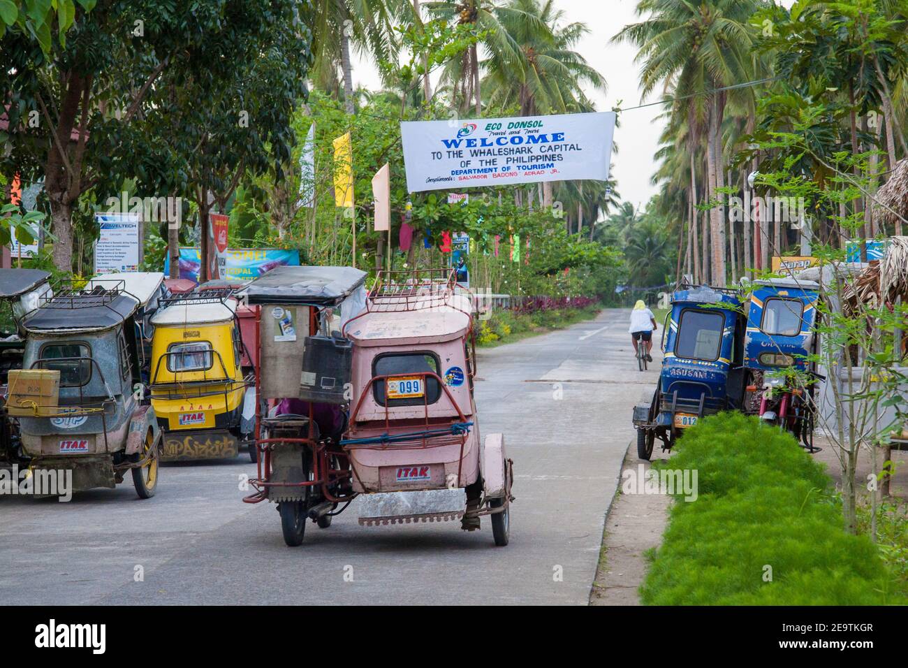 A street with motorcycle taxis and a whale shark banner over head, in Donsol, Sorsogon Province, Luzon, Philippines. Stock Photo