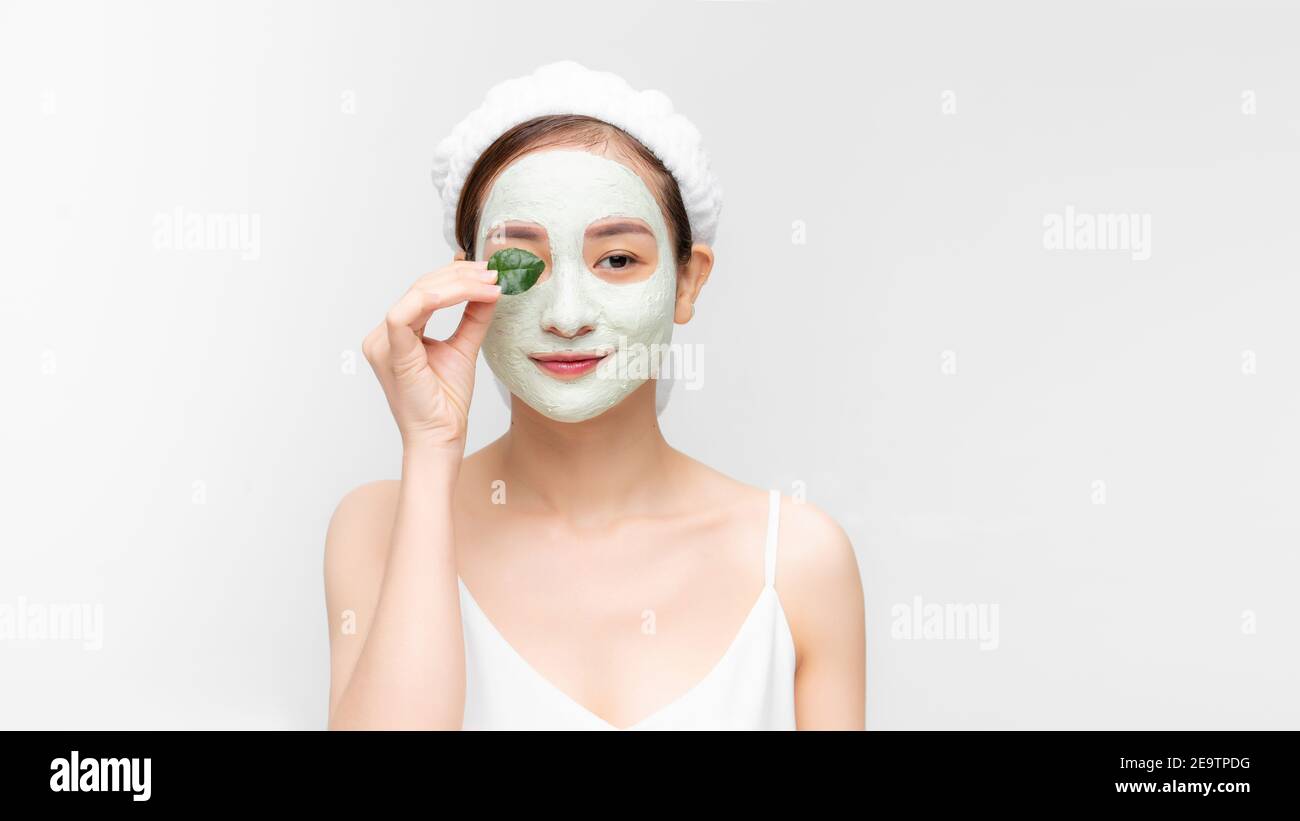 Young beautiful woman in face mask of therapeutic blue mud. Spa treatment, self care and healthy skin. Copy space, white background Stock Photo