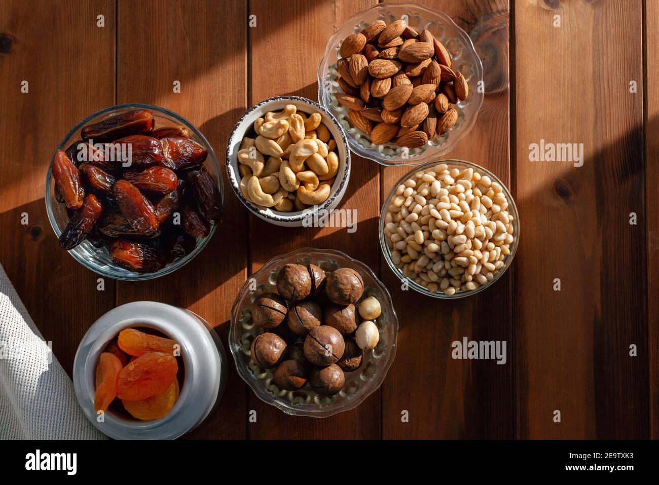 Different dried fruits and nuts under natural sunlight on wooden table. Overhead, from above Stock Photo