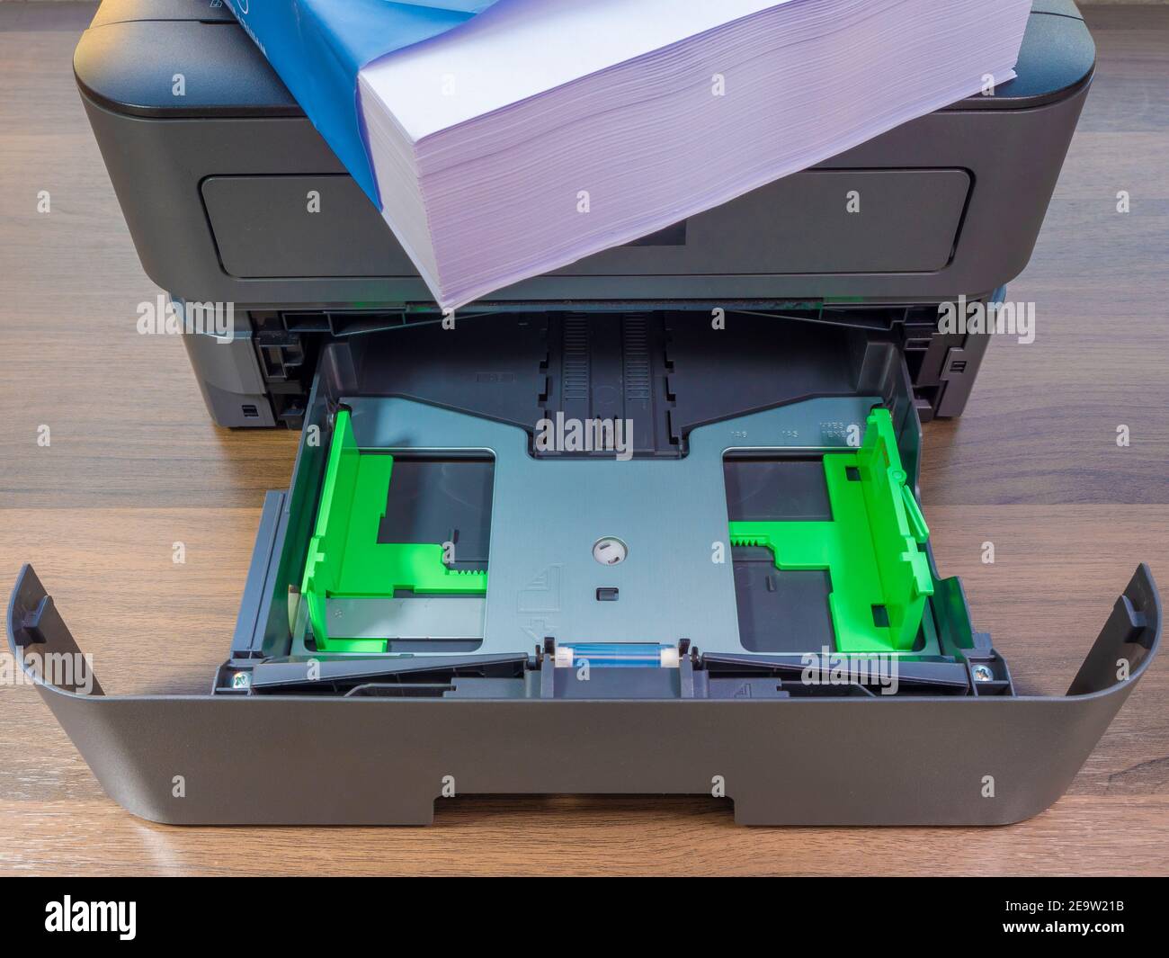 Closeup POV shot of an empty tray, with a fresh ream of white paper on top of the printer, on an office desk. Stock Photo