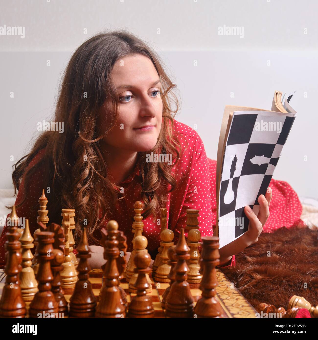Adult woman learns chess while sitting with a book at a chessboard ...