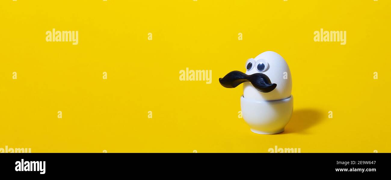 Easter funny eggs man with black mustache. Banner. Creative minimal easter egg concept. White egg on yellow background. Copy space. Stock Photo