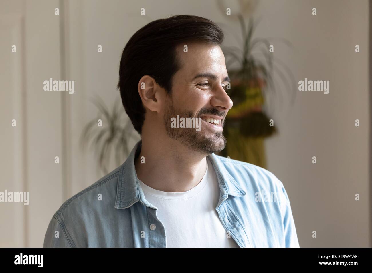 Handsome smiling bearded millennial man distracted from camera looking aside Stock Photo