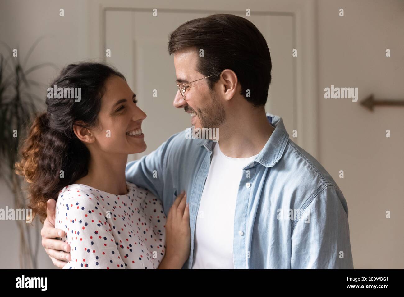 Affectionate millennial couple cuddling looking in eyes with love Stock Photo