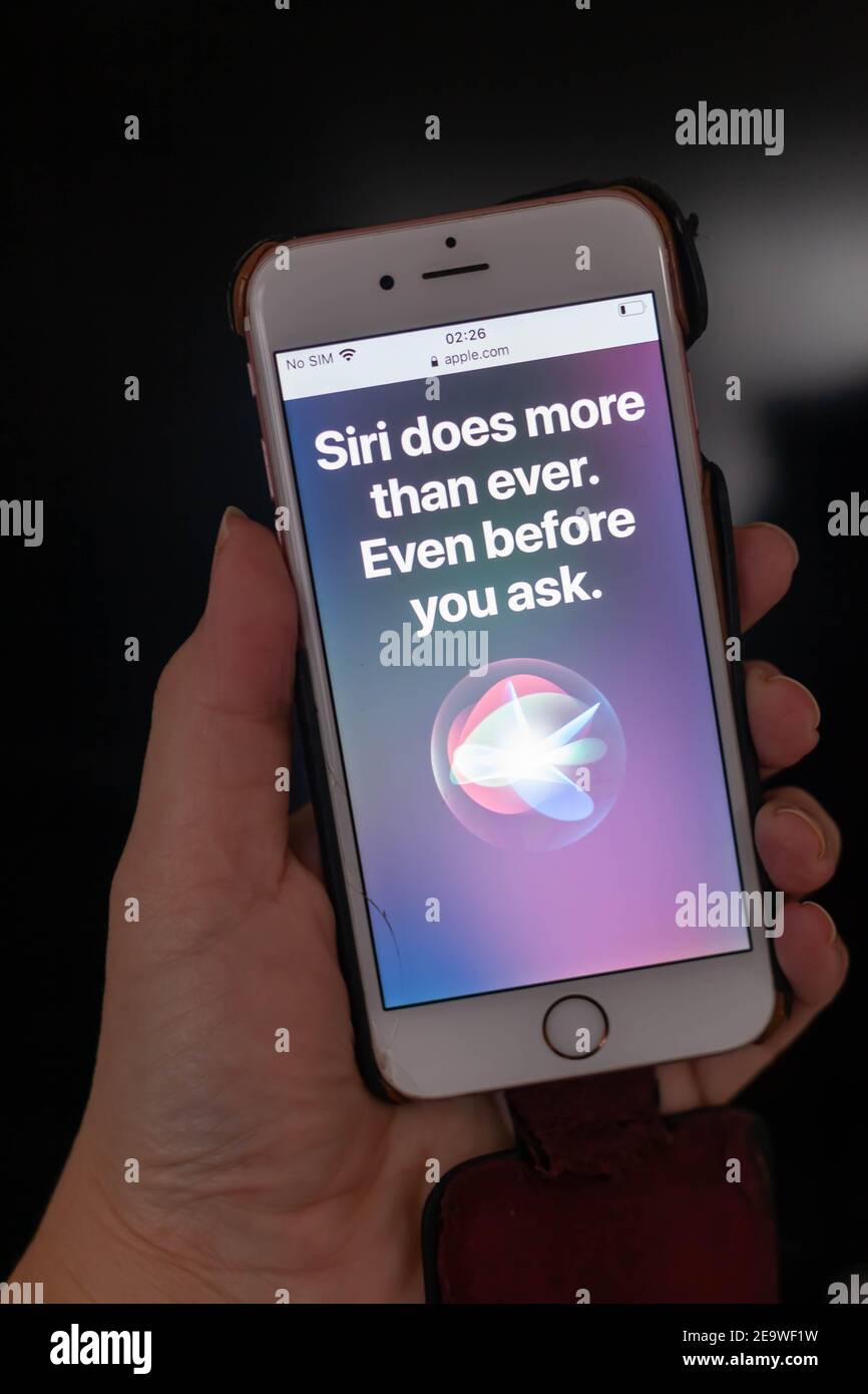 High resolution close-up of a hand holding an i-phone with SIRI app and logo on screen Stock Photo