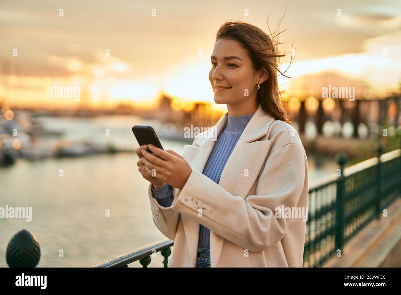 Young hispanic woman smiling happy using smartphone at the city Stock ...