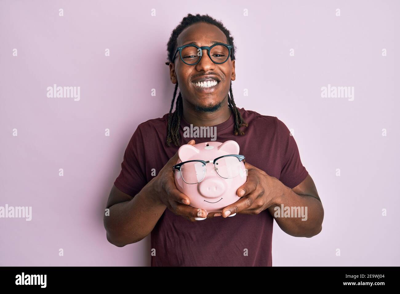 African american man with braids holding piggy bank with glasses ...