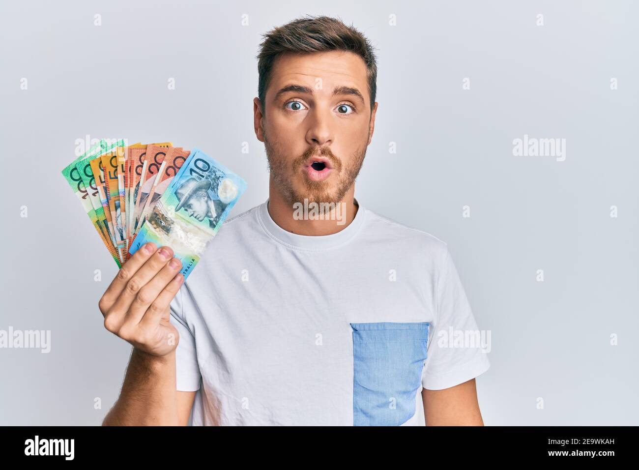 Handsome Caucasian Man Holding Australian Dollars Scared And Amazed With Open Mouth For Surprise 