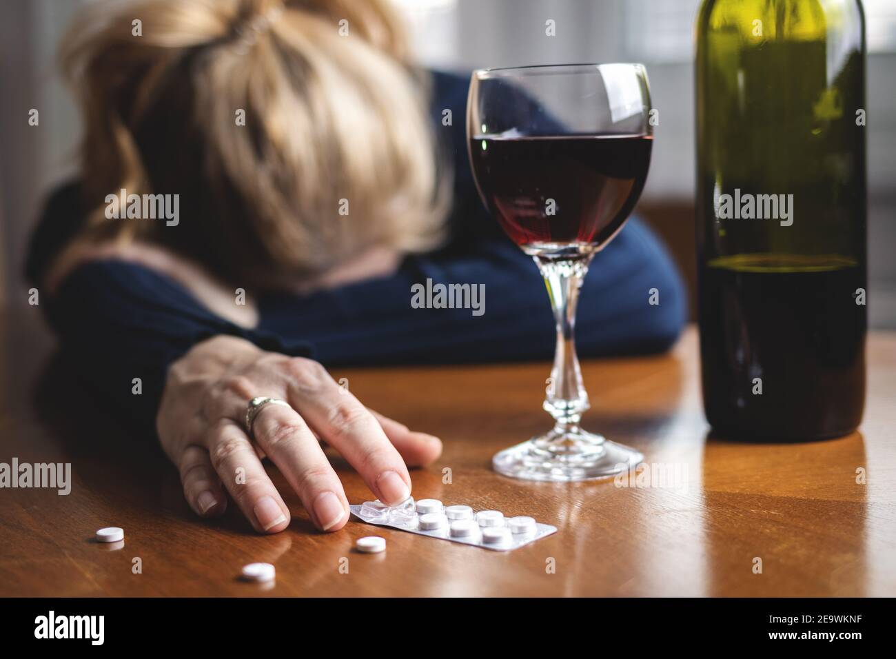 Woman after drug overdose and drinking red wine. Drugs and alcohol addiction social issues. Drunk female at home alone. Alcoholism concept Stock Photo