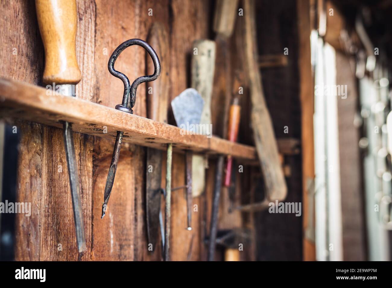 Vintage work tool in carpentry workshop. Hand drill, chisel and other tools on wooden background. Selective focus Stock Photo
