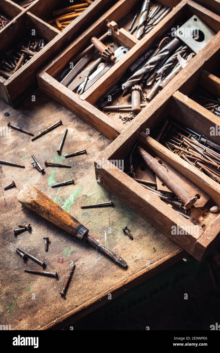 Screwdriver and bolts with toolbox on wooden table. Messy work tool in carpentry workshop. Vintage industrial equipment Stock Photo