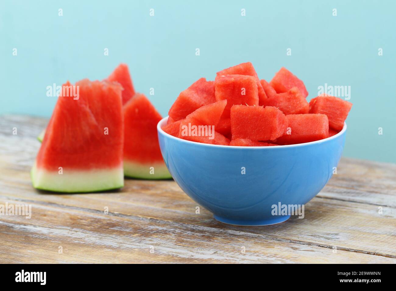 Juicy and refreshing cubes of watermelon in blue bowl on wooden surface Stock Photo