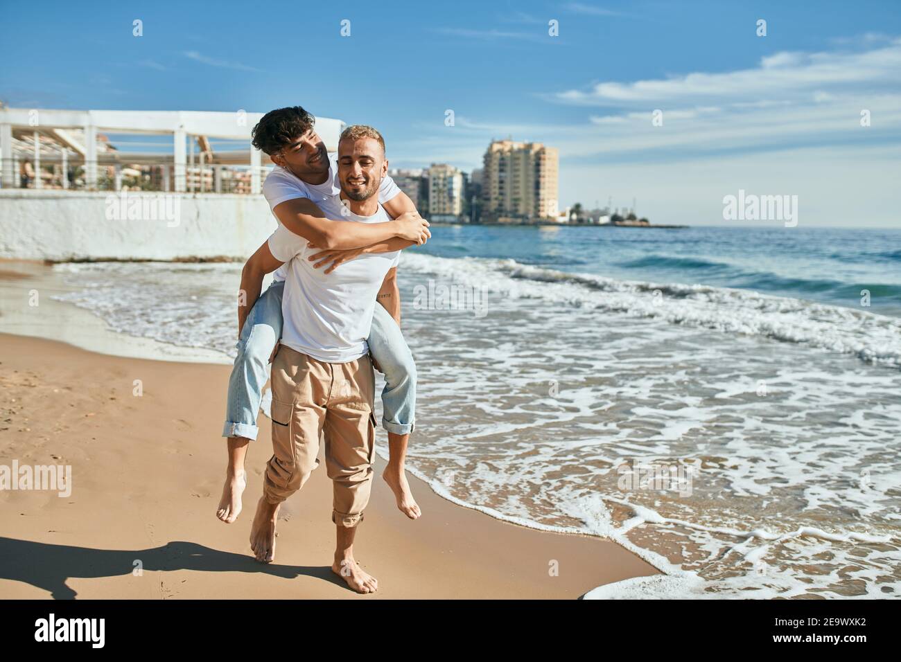 Lovely gay couple on piggyback ride at the beach Stock Photo - Alamy