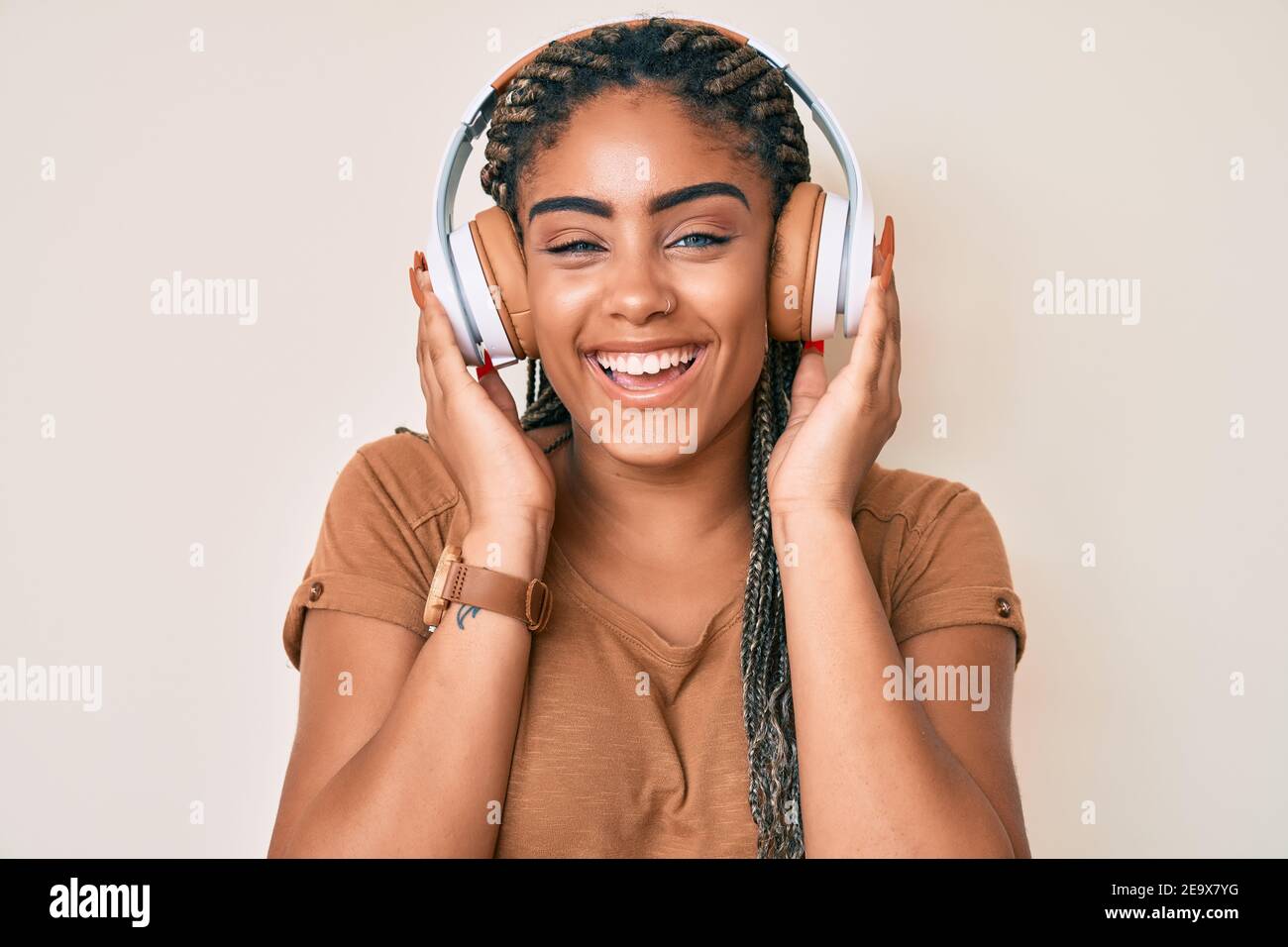 Young african american woman with braids listening to music using ...