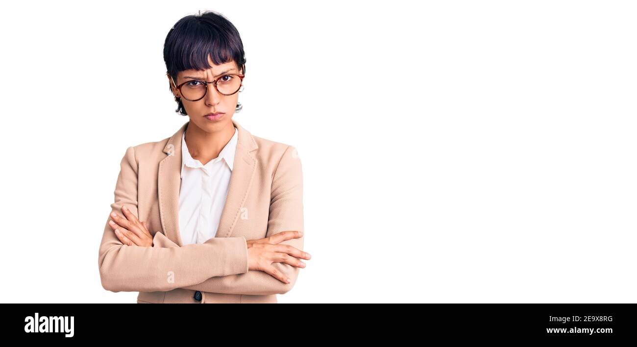 Young brunette woman with short hair wearing business jacket and glasses skeptic and nervous, disapproving expression on face with crossed arms. negat Stock Photo