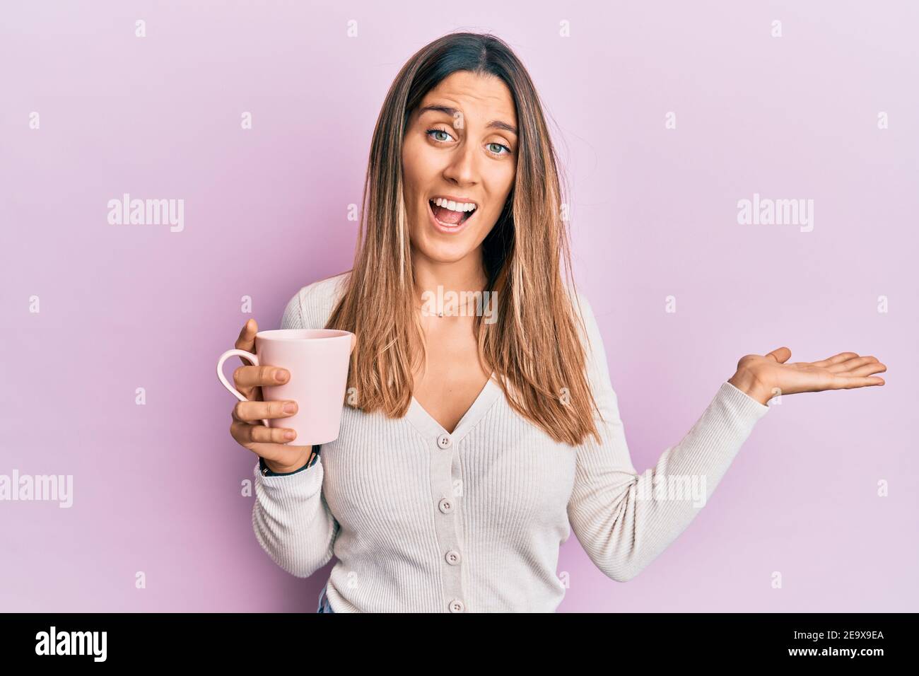 young woman drinking a cup of coffee celebrating achievement with happy smile and