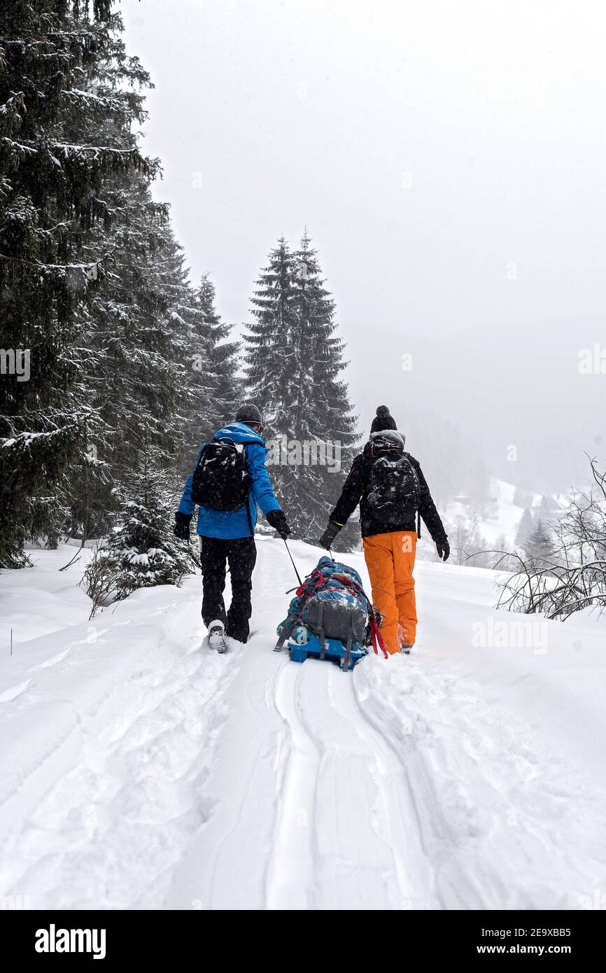 two persons back to lens pulling their baggage in winter time fogy coutryside Stock Photo