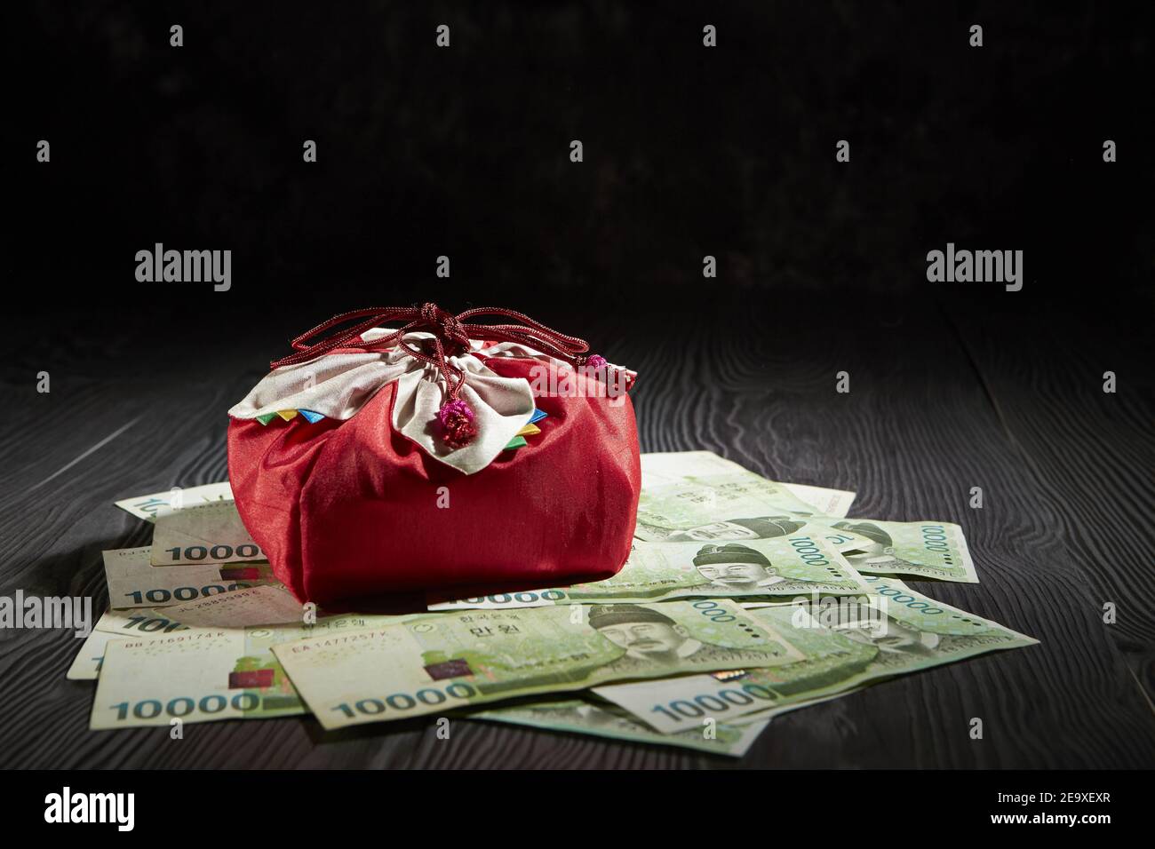 Closeup of a red gift bag placed on South Korean won, on a wooden surface Stock Photo