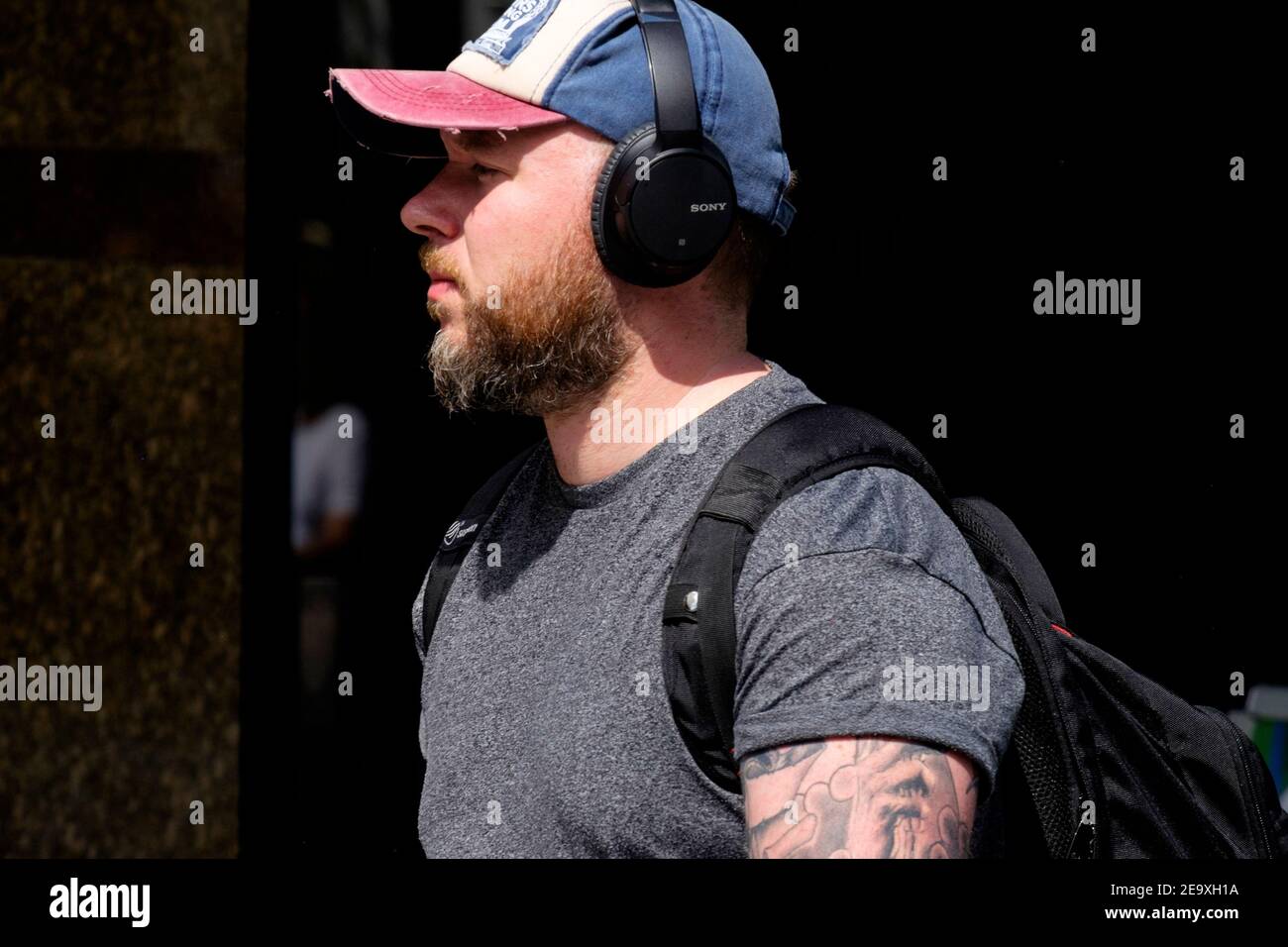 London street: male, 20s, beard, cap, Sony headphones. Stock Photo