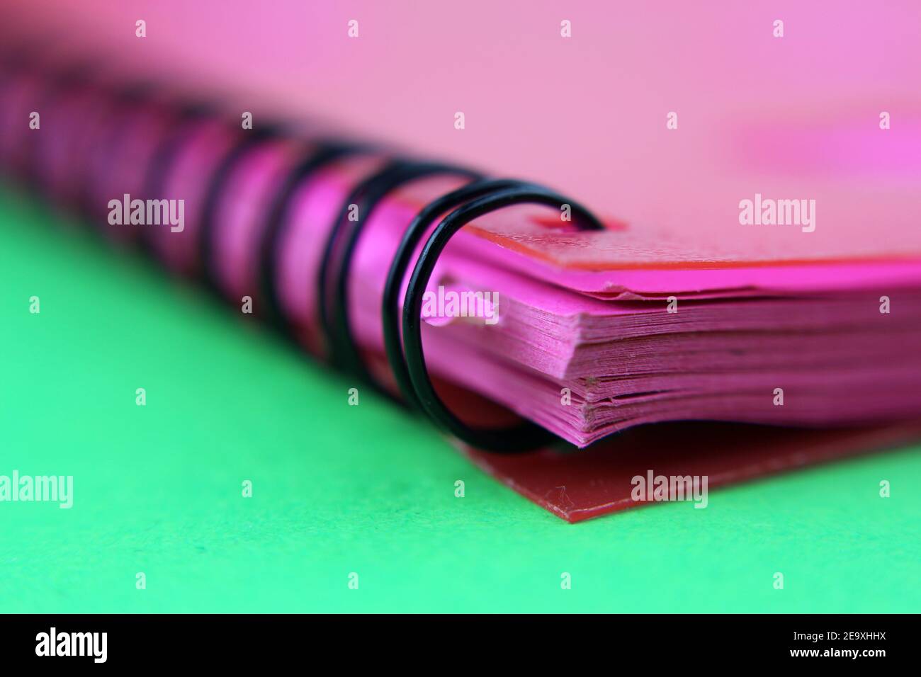 Spiral binder, pink notebook, foreground, desk background Stock Photo