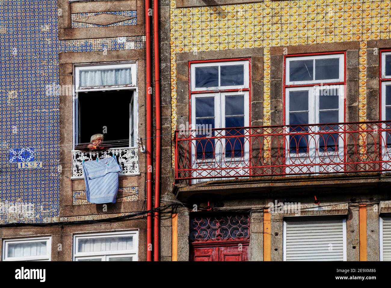 old woman looks out a window in the old town, Porto, Portugal, Europe Stock Photo