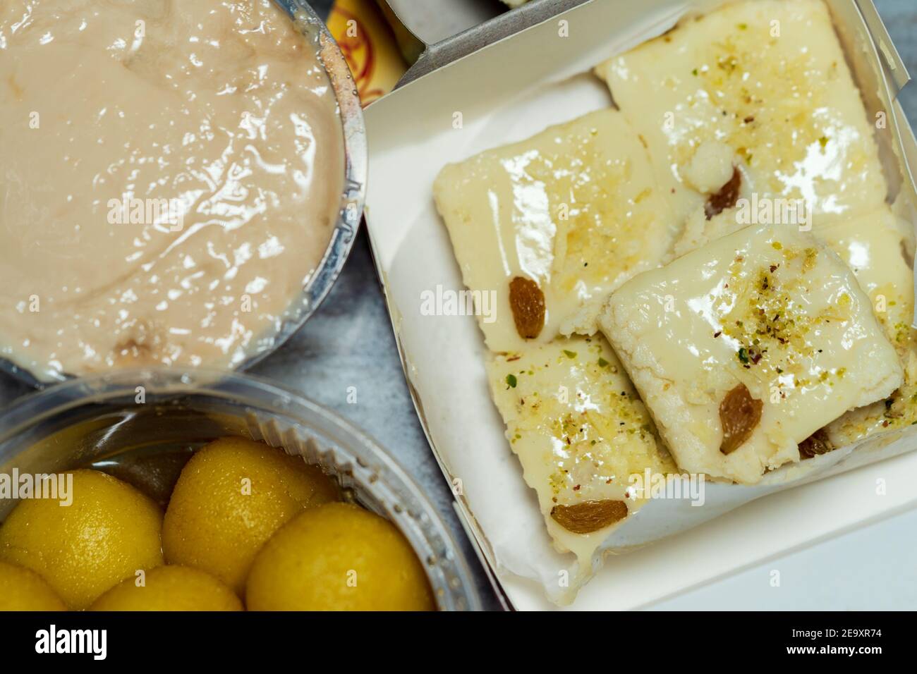 Assorted Indian Sweets or Desserts background. Stock image of Bengali Komola bhog rasgulla, milk Sandesh and mishti doi buffet arrangement. Stock Photo